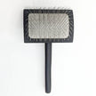 Black pet grooming brush with a textured surface on a white background