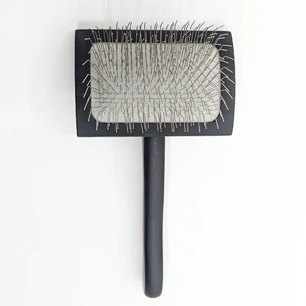 Black pet grooming brush with a textured surface on a white background