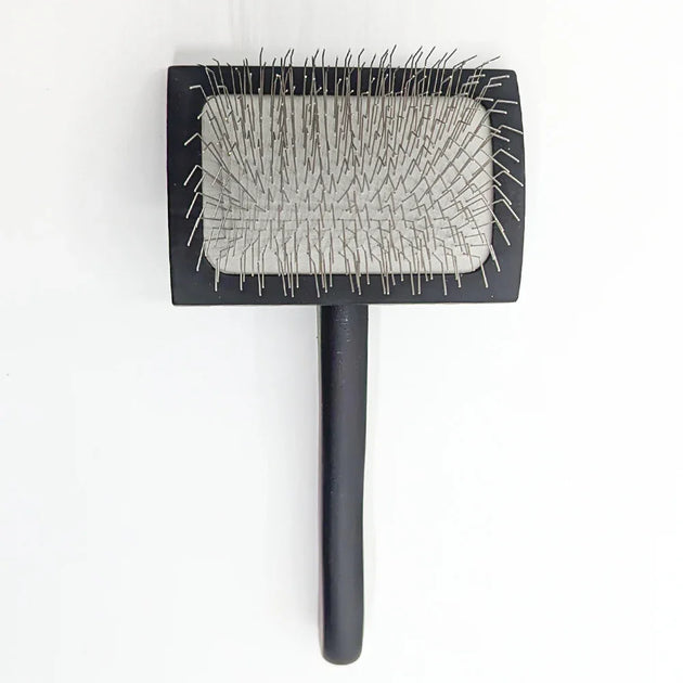 Black pet grooming brush with a textured surface on a white background