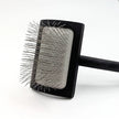 Pet grooming brush with black handle and clear bristle design on a white background