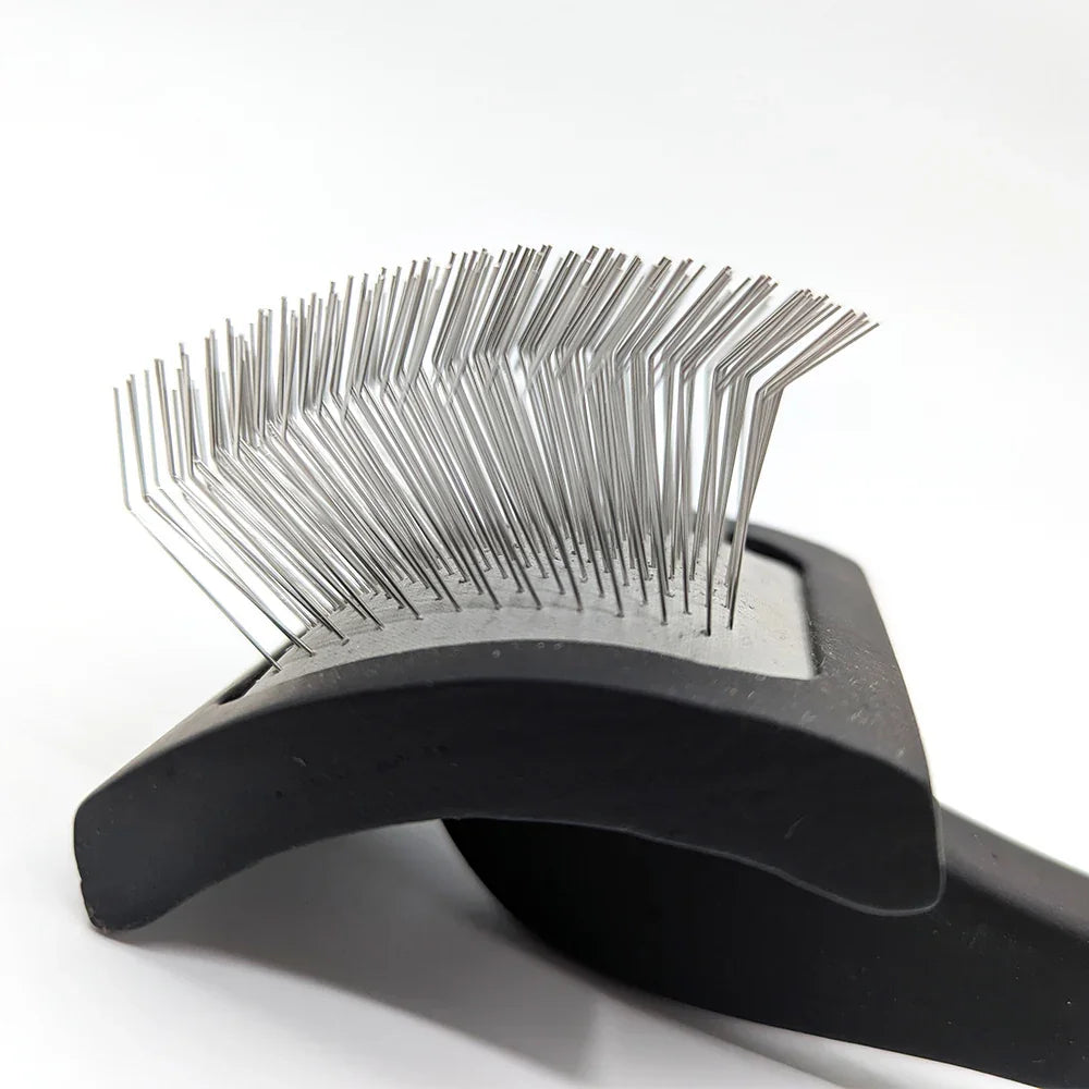 Pet grooming brush with metal bristles on a white background